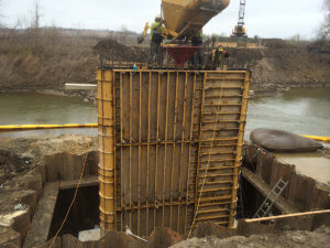 Crews pour concrete into the bridge support that extends into the ground.
